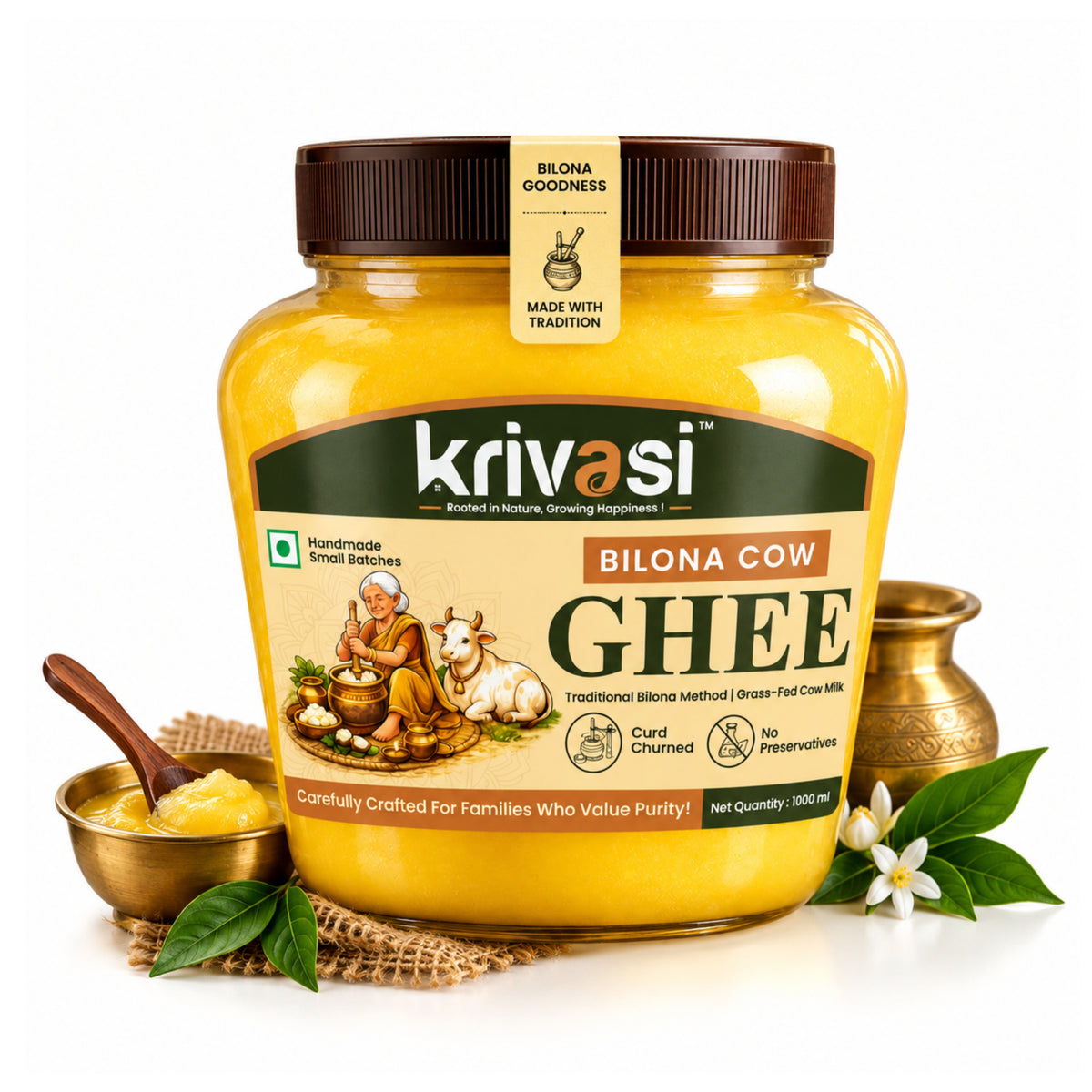 A jar of Krivasi Bilona Cow Ghee on a white background, styled with a small brass bowl of ghee, a wooden spoon, green leaves, and white flowers.